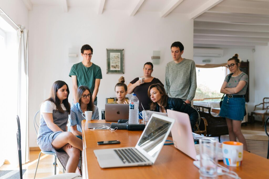 A team of professionals intently working around a table in a casual workspace, illustrating the flexibility and well-being supported by quality employee health plans.