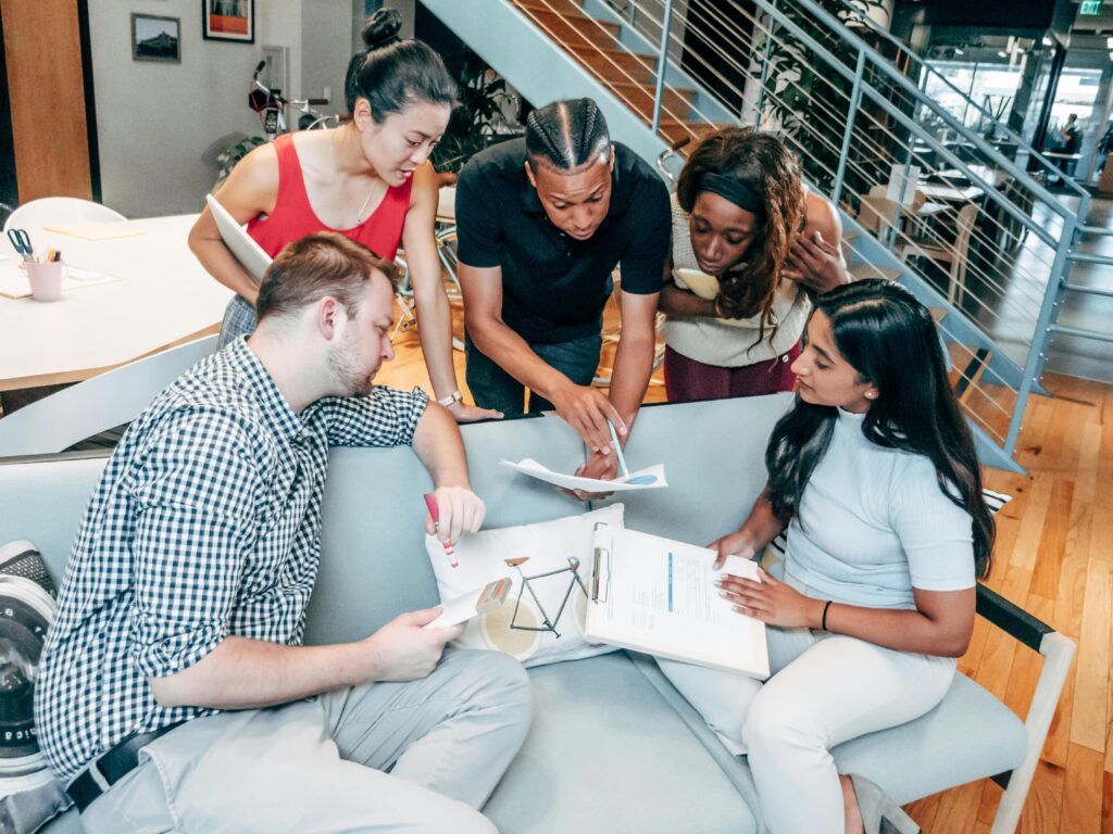 A diverse team gathered around documents in a creative office space, reviewing strategies supported by inclusive and flexible California insurance plans.