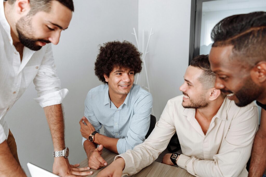 A diverse team of men sharing ideas in a relaxed office setting, representing the community-driven values supported by comprehensive California insurance plans.