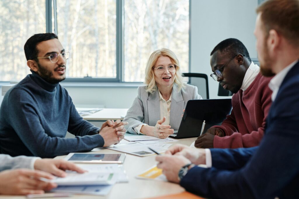 Professionals in a modern office setting engaged in a strategic conversation around a conference table, representing the professional stability enhanced by California insurance plans.