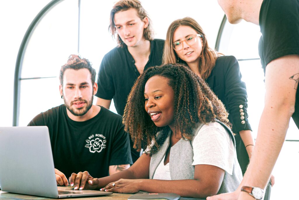 Diverse San Diego team collaborating around a laptop, reflecting the value of San Diego insurance benefits like dental and vision plans in supporting employee satisfaction.