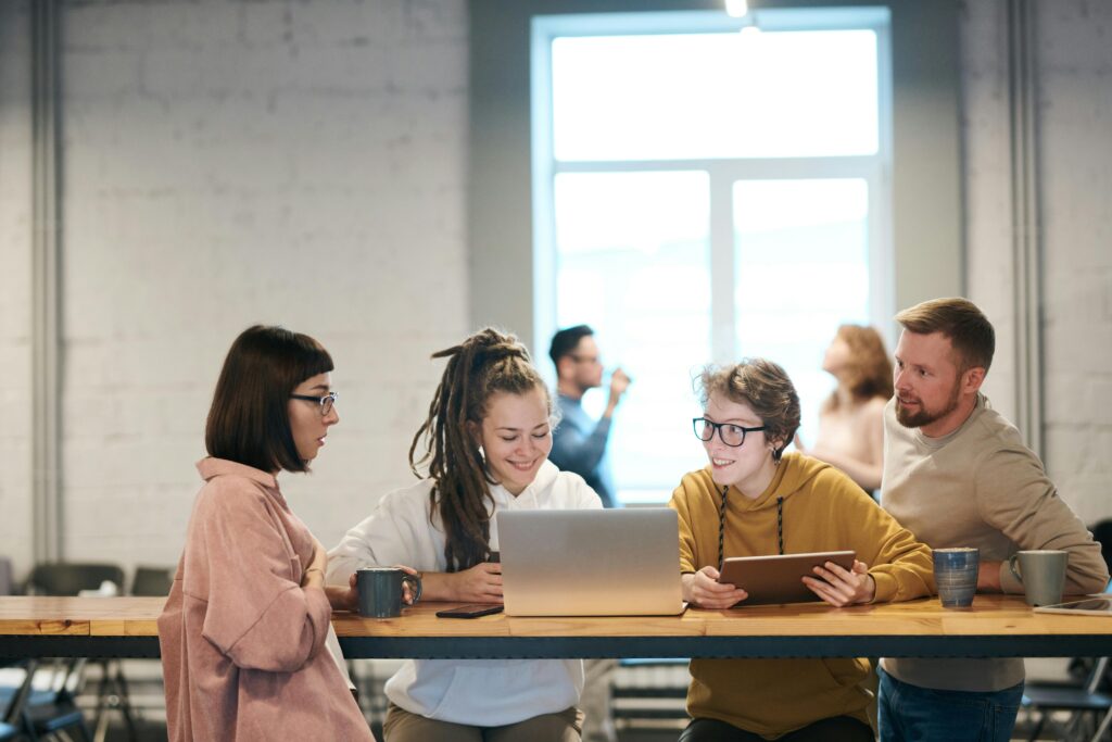A diverse group of young professionals collaborates on a project related to California insurance plans in a modern office setting.