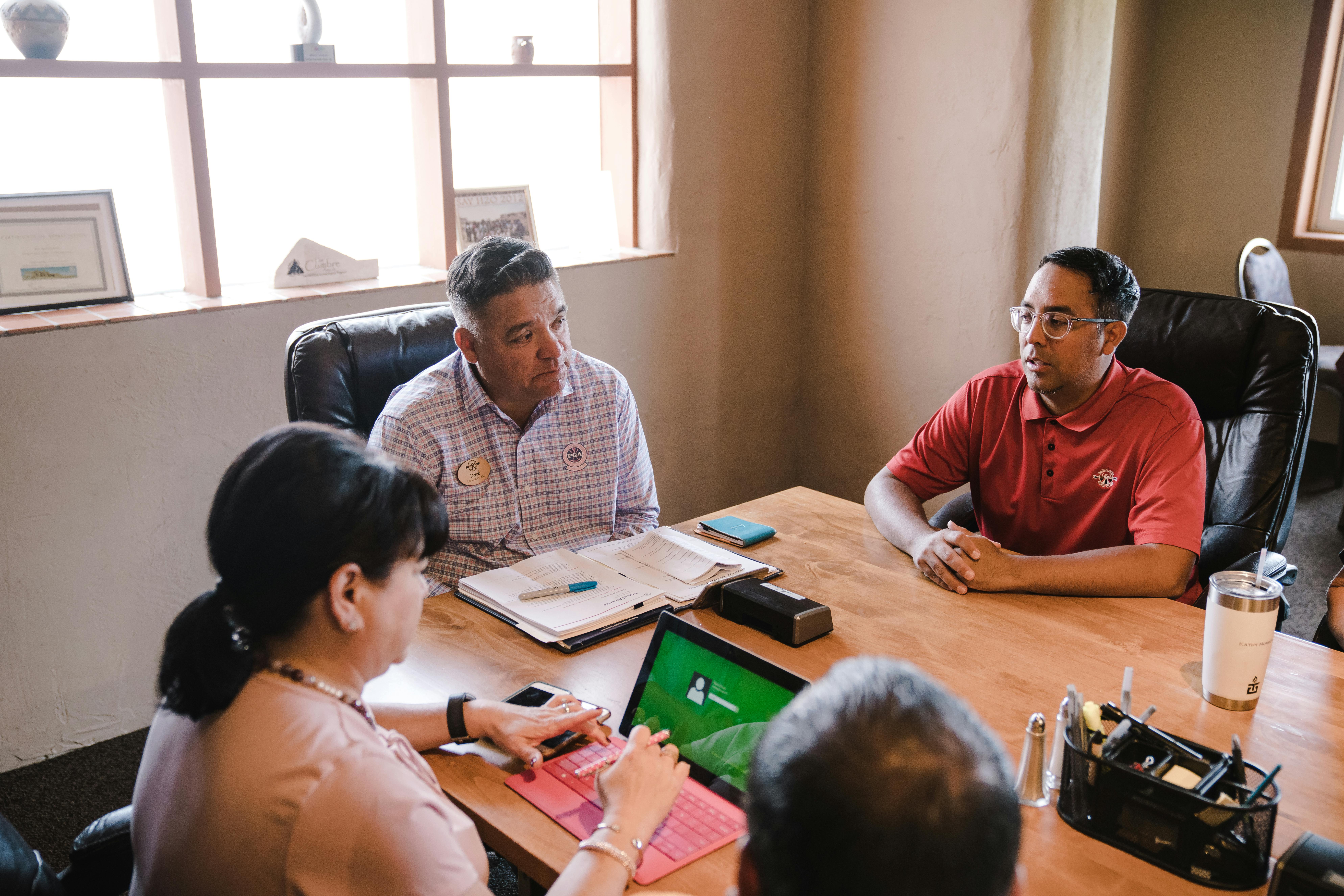 Team of professionals in a meeting room discussing strategies for improving employee health plans and workplace wellness benefits.