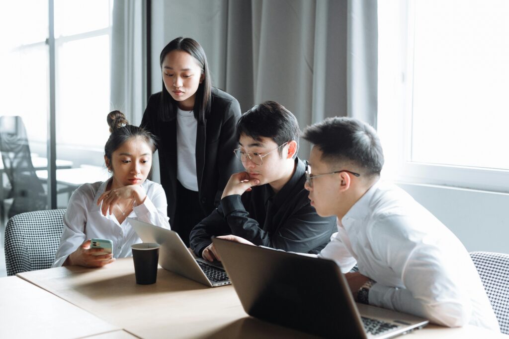 Focused team gathered around a laptop during a workplace meeting, exploring California insurance plans and employee benefit options.